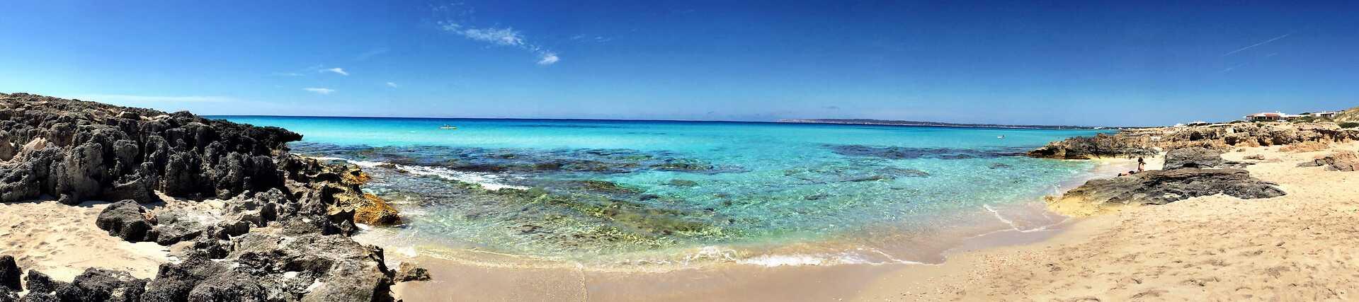 Strand in Formentera mit türkisblauem Wasser und hellem Sand.