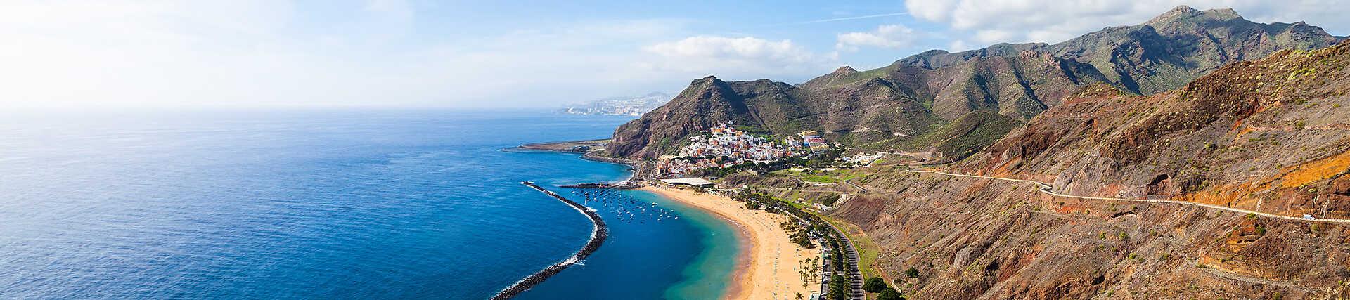 Blick von oben auf den goldenen Sandstrand Playa de las Teresitas, die Bucht mit Wellenbrecher und das Anaga-Gebirge im Hintergrund.