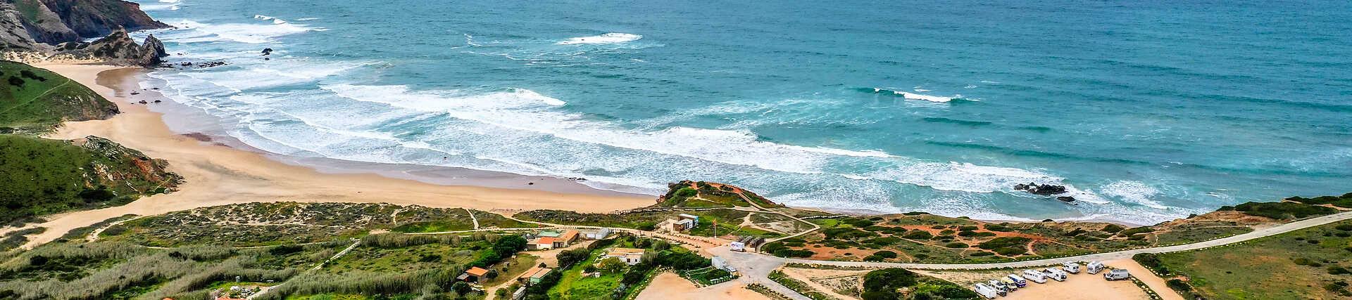 Strand Praia do Amado in Portugal bei Sonnenuntergang mit Wellen und Sand.