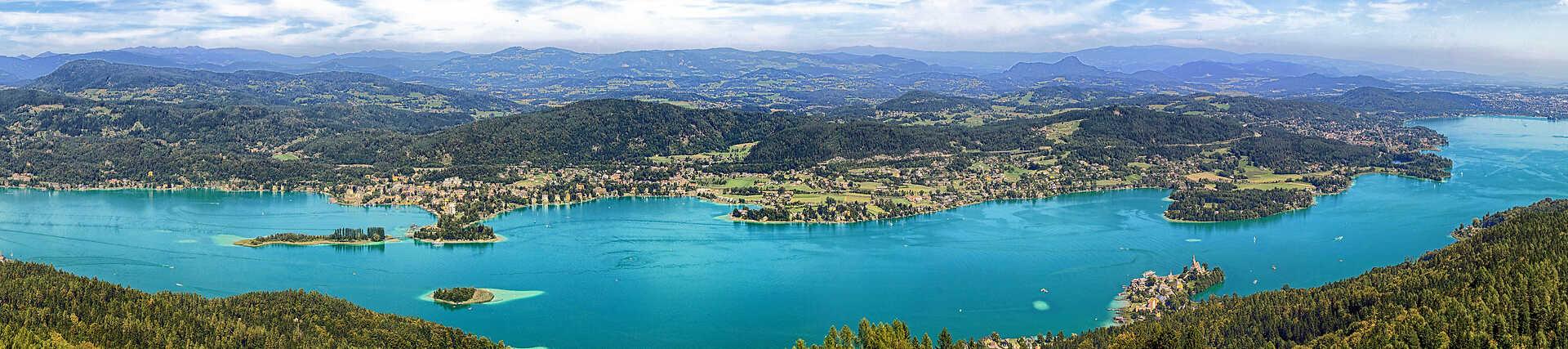 Ein idyllisches Bild des Wörthersees in Österreich mit klarem blauem Wasser und Bergen im Hintergrund.