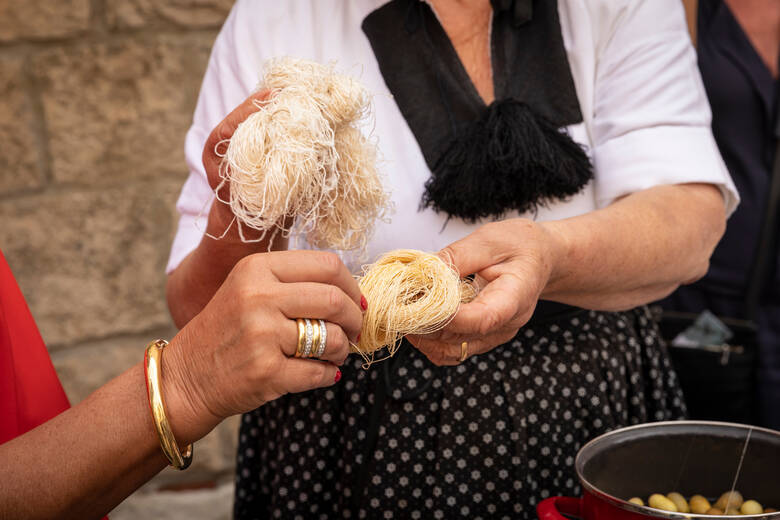 Frau in einer Tracht hält Seidengarn in der Hand 