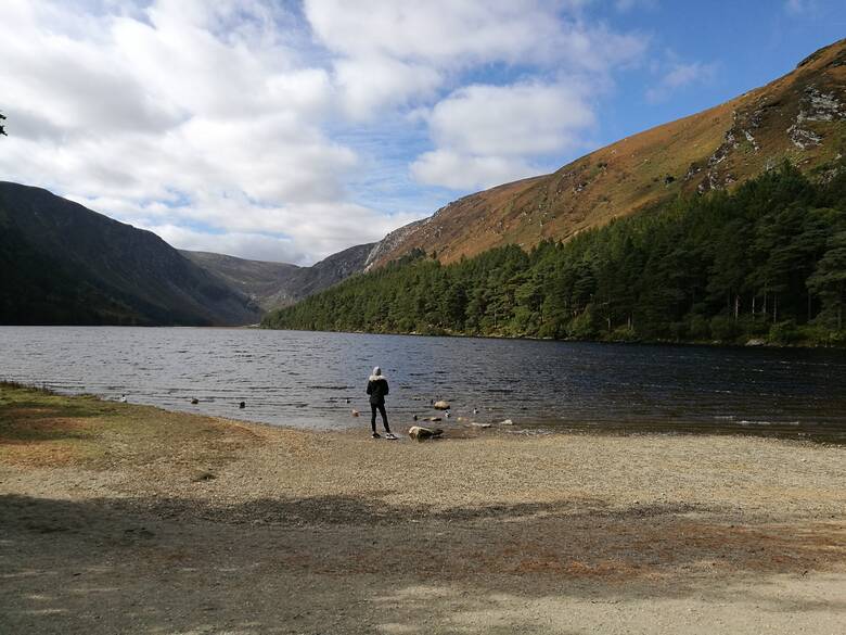 Frau blickt auf einen See im Wicklow Mountains National Park in Irland 