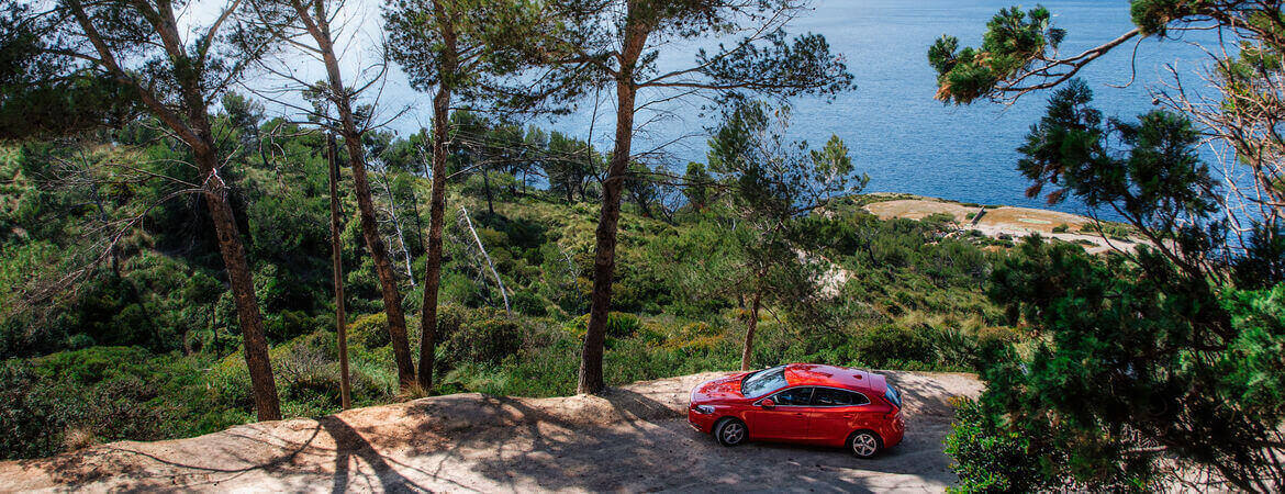Rotes Auto steht an der Küste in Ibiza