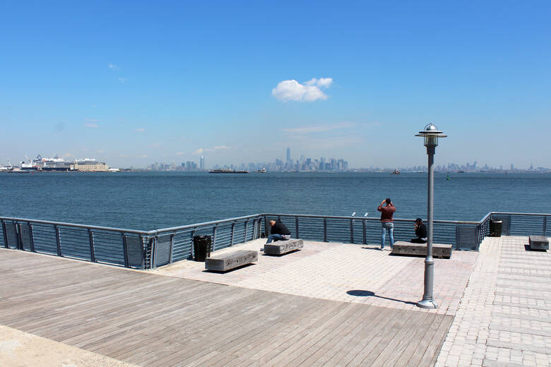 Mann steht am Pier in Staten Island und blickt auf Manhattan
