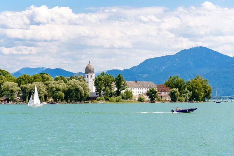 Chiemsee, Bayern, Germany. Beautiful view on lake with alps mountains, blue sky with clouds, monastery, church on island Frauenchiemsee