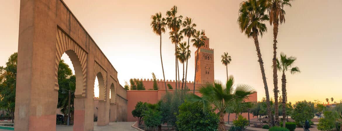 Moschee und Palmen in Marrakesch bei Sonnenuntergang