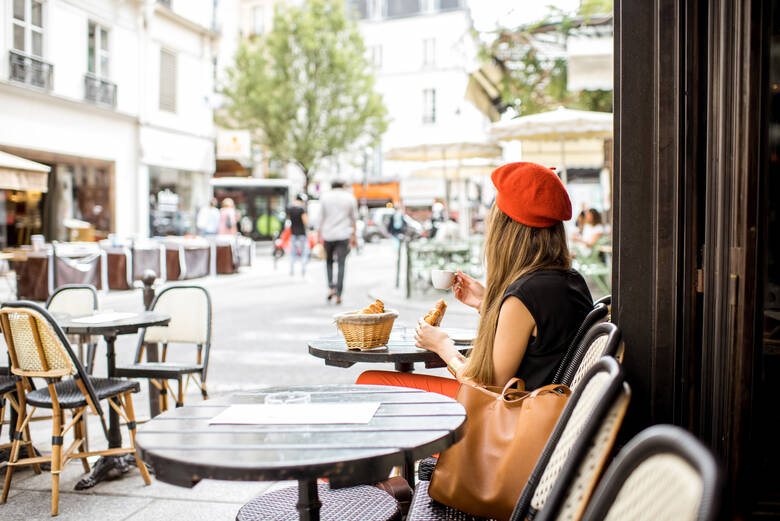 Frau sitzt in einem französischen Café und isst Croissants