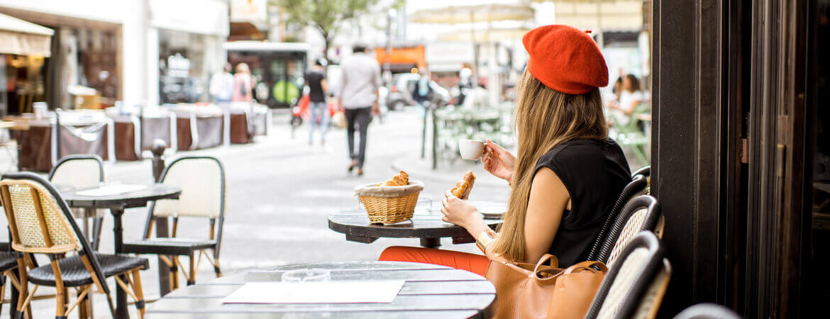 Frau sitzt in einem Café in Paris und isst Croissants