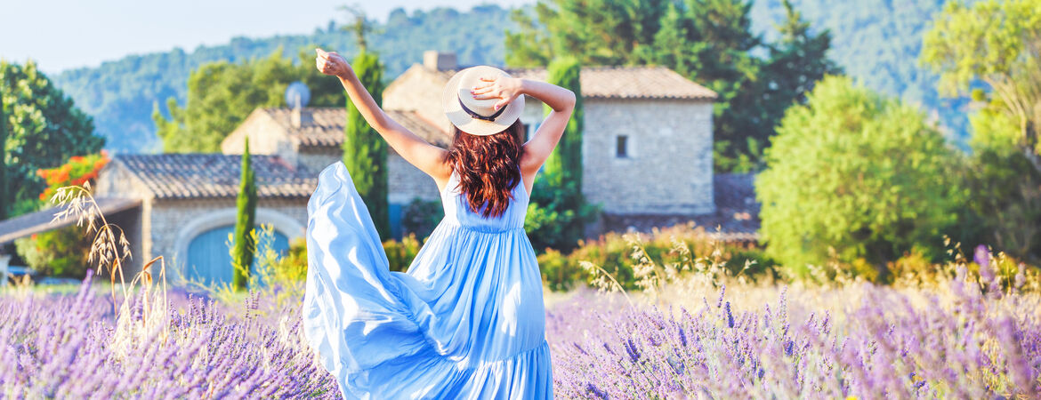 Frau mit Sonnenhut tanzt in einem Lavendelfeld