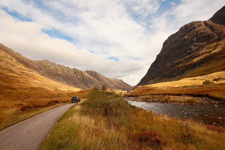 Auto fährt durch die herbstlichen Highlands in Schottland 