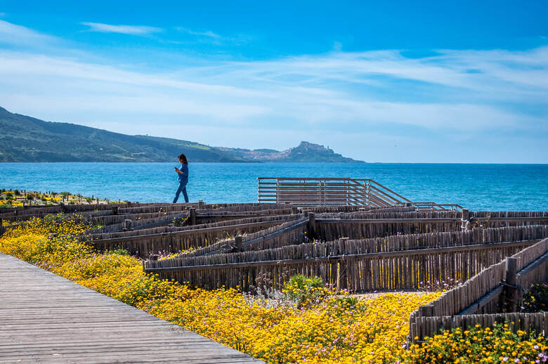 Frau läuft am Meer in Sardinien entlang 