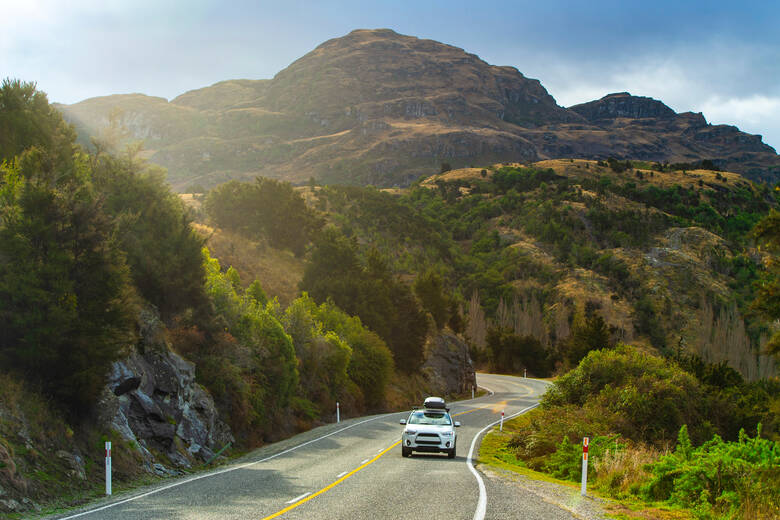 Auto fährt durch Berglandschaft in Neuseeland