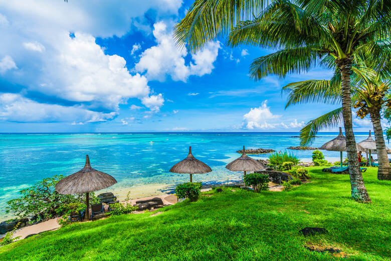 Sonnenschirme und Palmen an einem Strand auf Mauritius