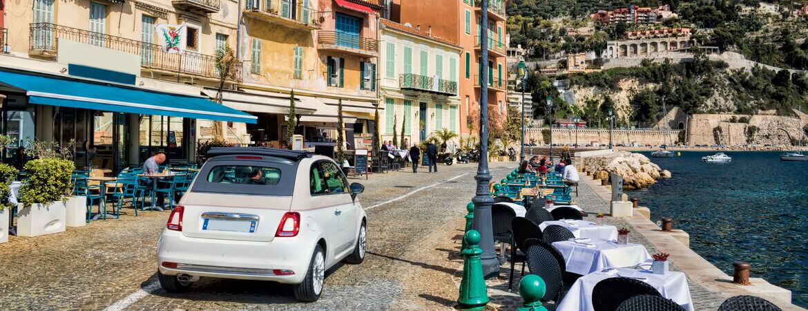 Kleines Auto fährt in Nizza an der Küste entlang