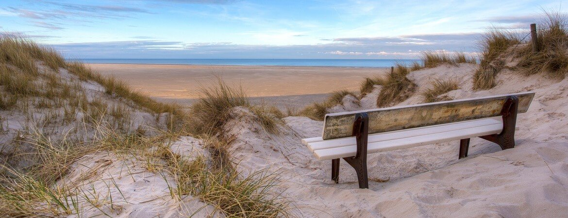 Bank auf den Dünen an einem Sandstrand