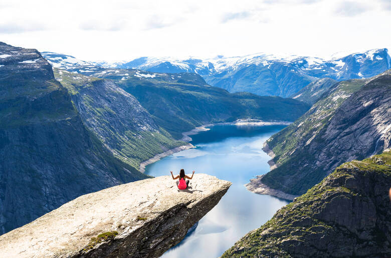 Frau entspannt auf der sogenannten Trolltunga in Norwegen und schaut auf den Fjord