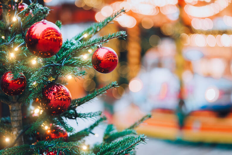 Weihnachtsbaum mit roten Kugeln vor einem Karussell