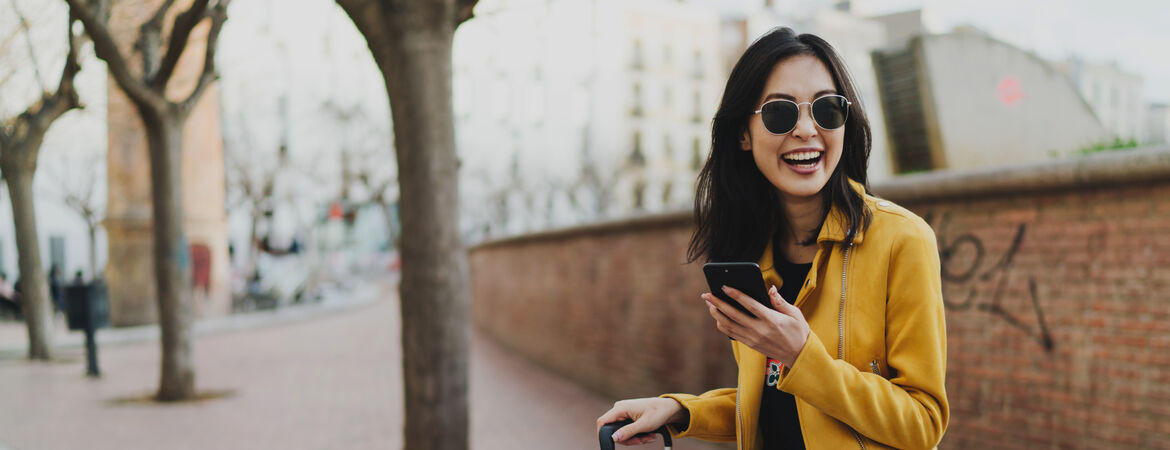 Frau lächelt und hält ein Smartphone in der Hand