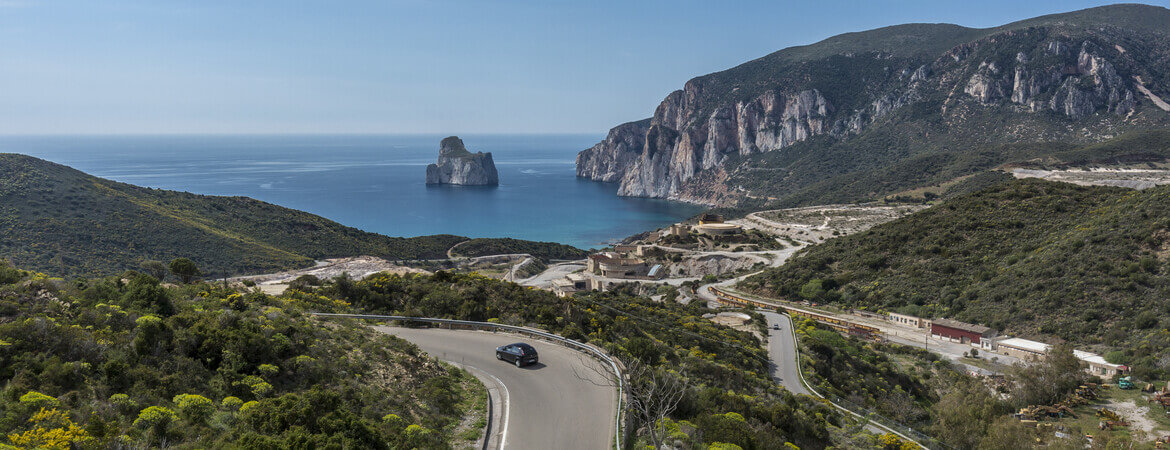 Auto fährt entlang einer Küstenstraße auf Sardinien