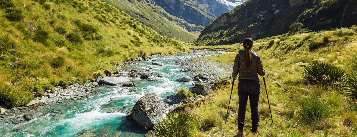 Frau landert durch eine Berglandschaft in Neuseeland