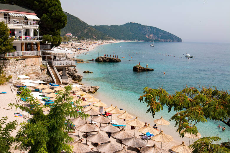 Sonnenschirme und Liegen am Strand von Dhërmi in Albanien