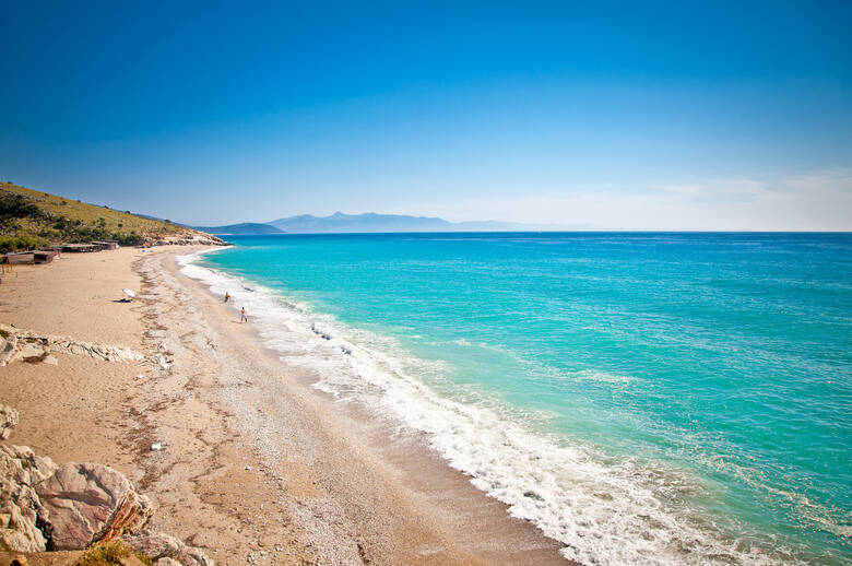 Blaues Wasser und feiner Kies an einem Strand in Albanien
