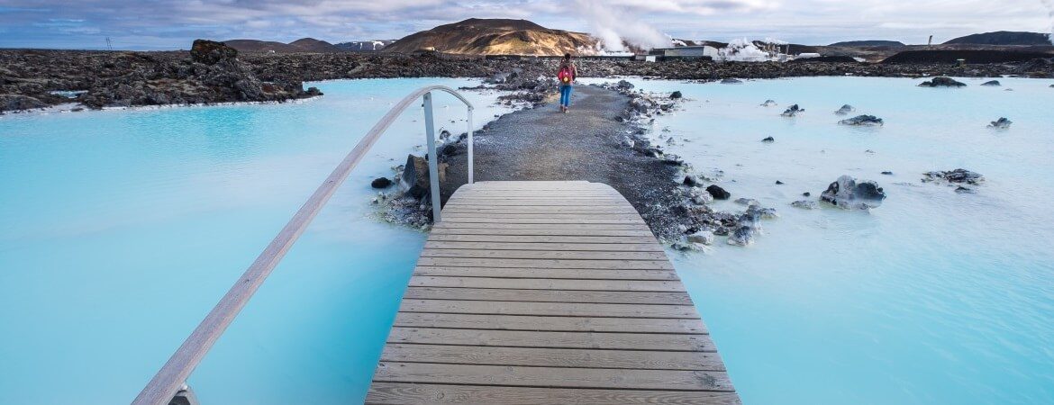 Frau läuft über eine Brücke zur Blauen Lagune in Island
