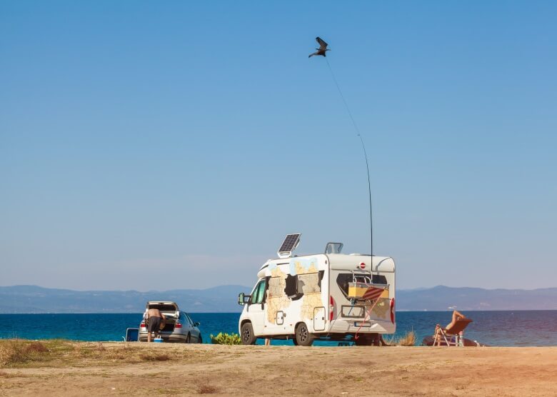 Urlauber mit Camper mit Solarmodulen am Strand