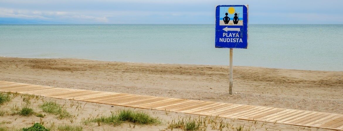 Hinweisschild "FKK-Strand" am Strand in Spanien