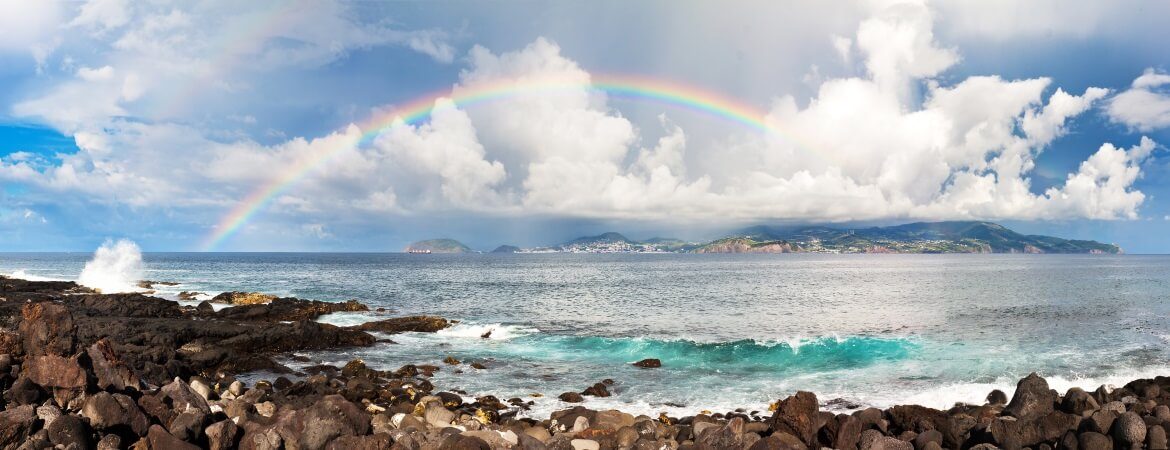 Regenbogen über Steinstrand auf den Azoren