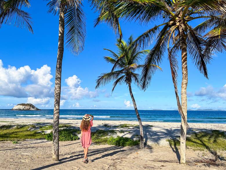Frau steht am Palmenstrand von Venezuela und schaut auf das Meer