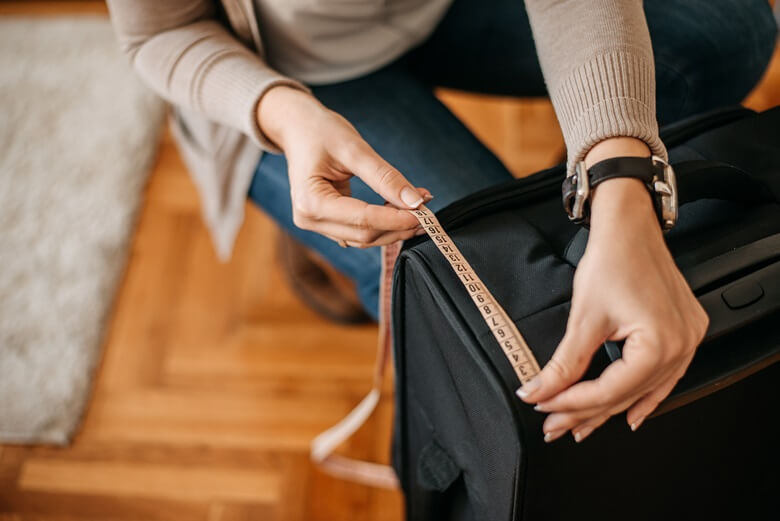 Frau misst die Größe Ihres Handgepäckkoffers