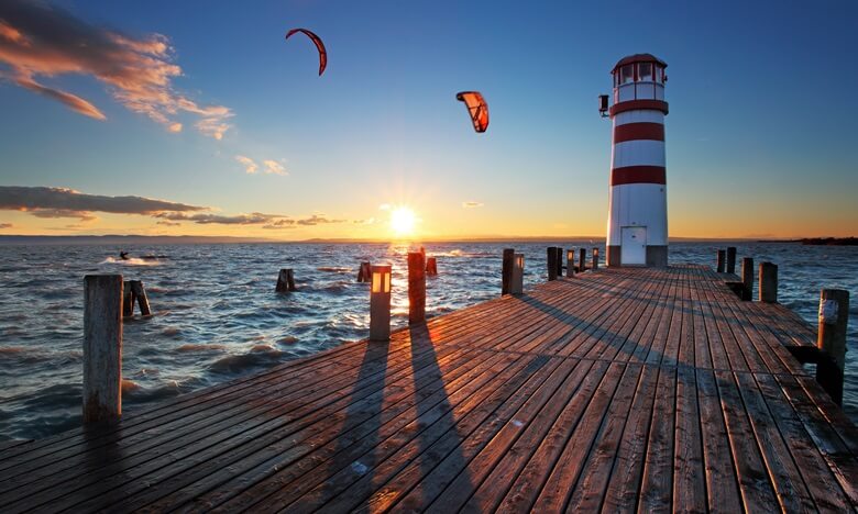 Steg mit Leuchtturm und Surfern am Neusiedler See in Österreich