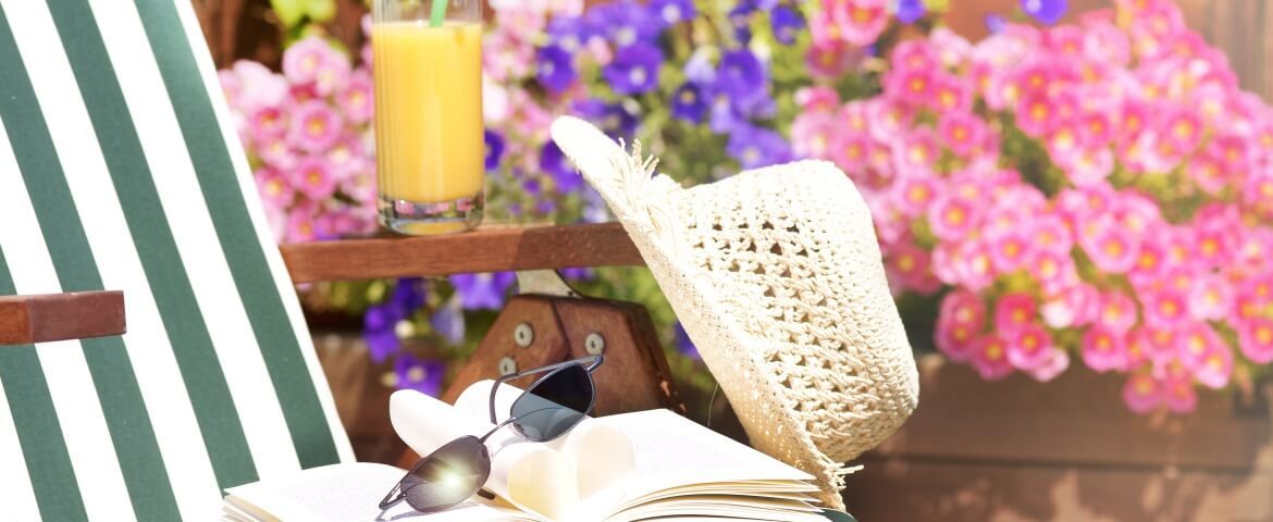 Gartenstuhl mit Buch, Sonnebrille und Hut