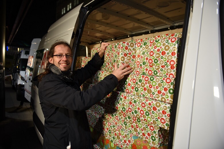 Mann packt Geschenke in einen Transporter