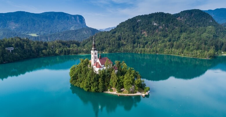 Blick über den klaren Bleder See mit Kirche Maria Himmelfahrt in Slowenien