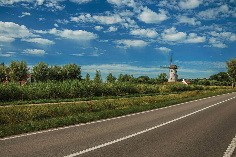Landstraße mit Windmühle in der Region Flandern in Belgien