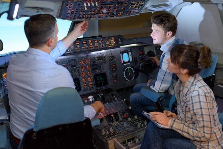 Ein Pilot erklärt seinen Gästen einen Flugsimulator