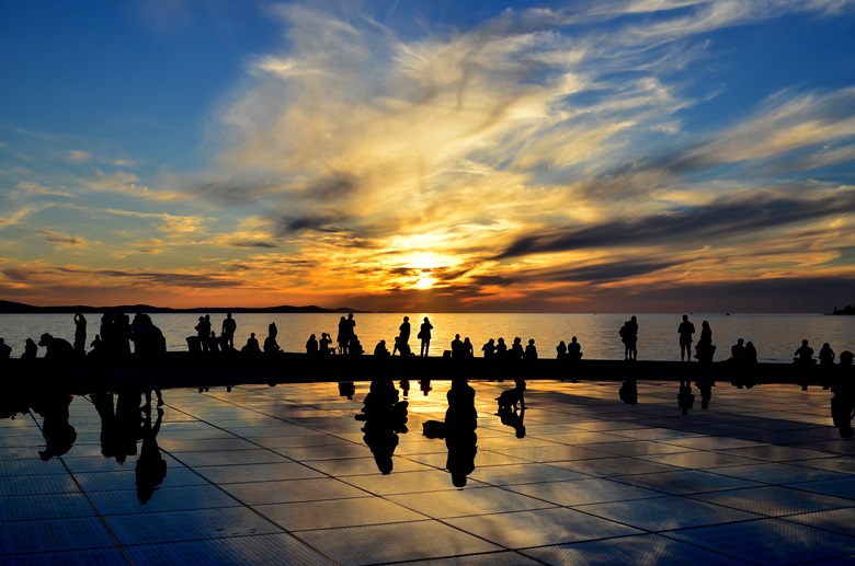 Menschen treffen sich in der kroatischen Stadt Zadar abends am Hafen