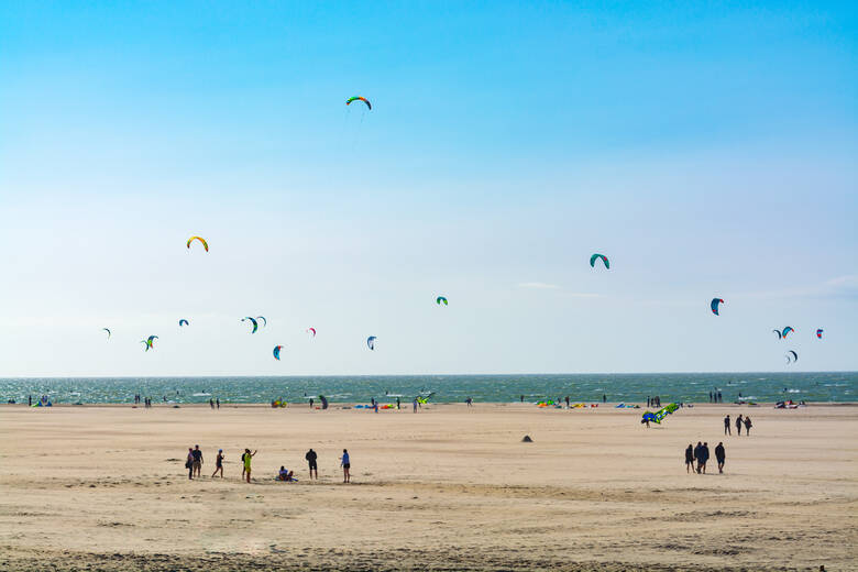 Menschen lassen am Strand von Renesse Drachen steigen