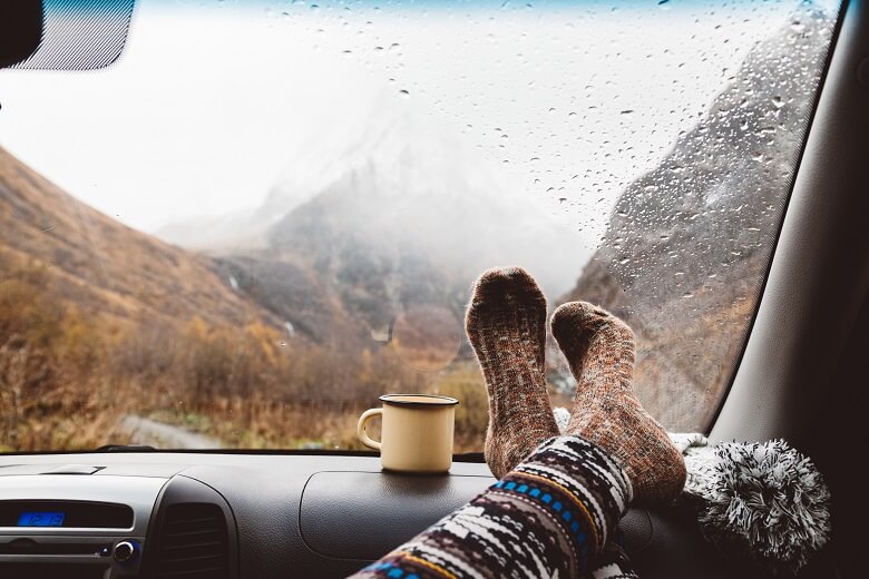 Füße und Kaffeetasse auf einer langen Autofahrt