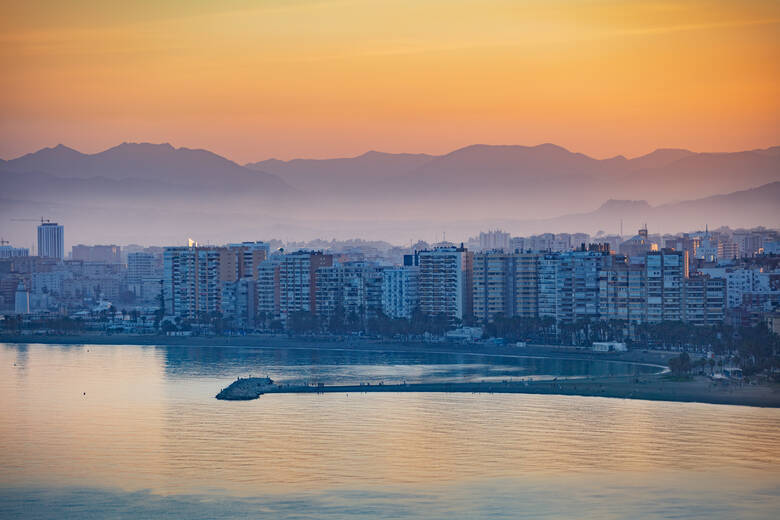 Stadtstrand bei Sonnenuntergang vor den Hochhäusern von Malaga 