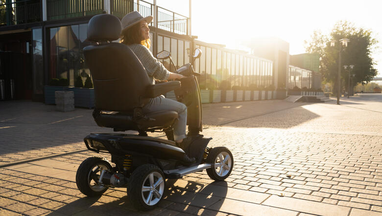 Frau fährt mit einem elektrischen Rollstuhl über das Hotelgelände.