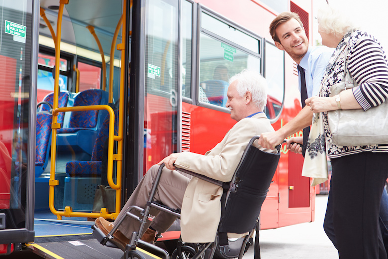 Busfahrer hilft Mann im Rollstuhl in den Bus