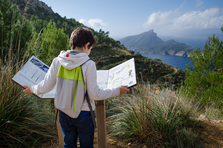 Kind liest ein Schild auf einer Wanderung auf Mallorca