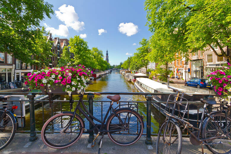 Sommerliche Gracht in Amsterdam, Aussicht von einer Brücke mit Fahrrädern und Blumen