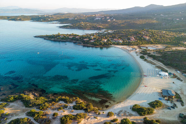 Luftaufnahme der Bucht Cala Sassari mit grüner Vegatation und blauen Meer