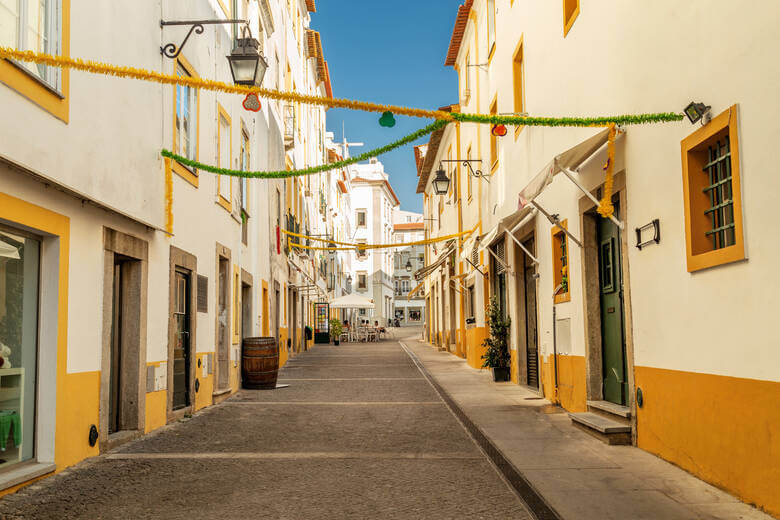 Weiß-gelb gestrichene Häuser entlang einer Gasse in Evora