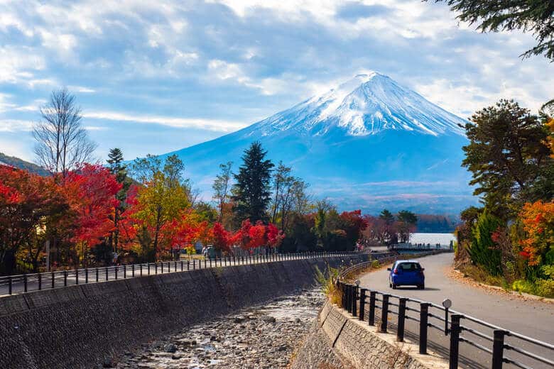 Auto fährt durch eine herbstliche Landschaft mit Blick auf den Mount Fuji