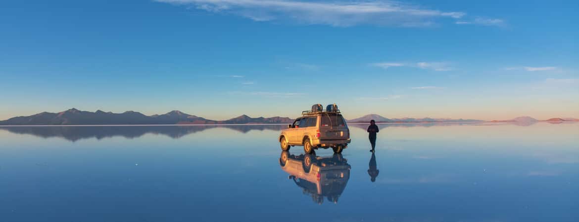 Auto und Mensch stehen in der Salzpfanne Salar de Uyuni in Bolivien